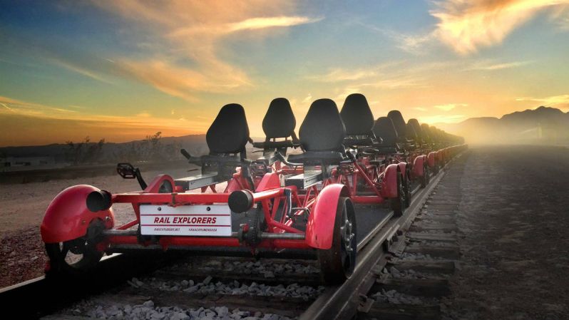 Rail Explorers rail bikes lined up on a train track with the sunrise in the background.