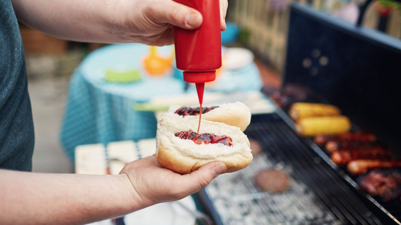 man putting ketchup on hot dog