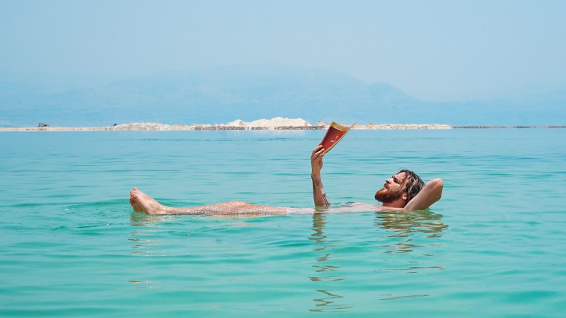 man reading a book while swimming