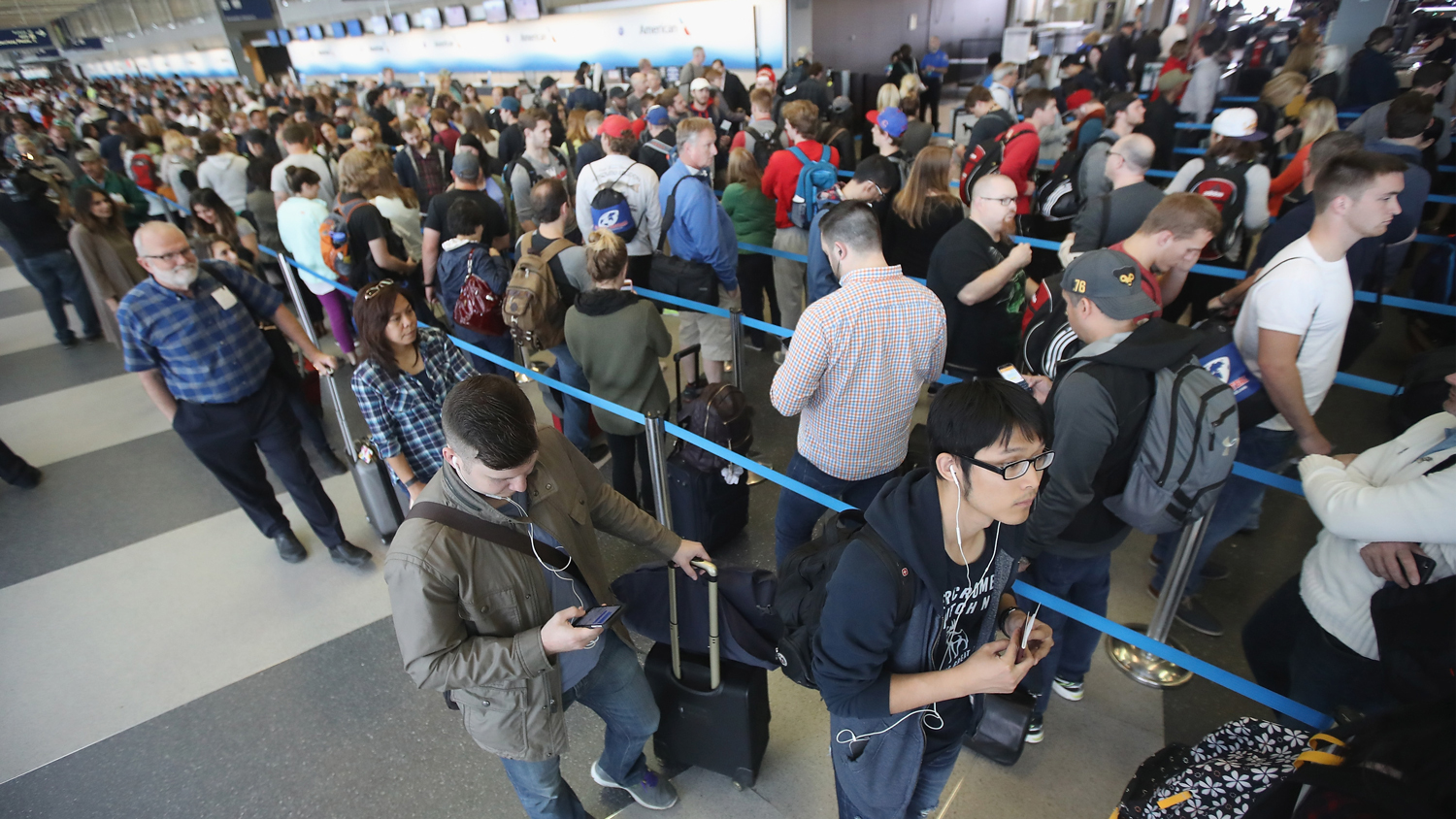 Long line of travelers waiting at an airport security checkpoint.