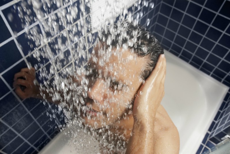 A man taking a shower in the bathtub.
