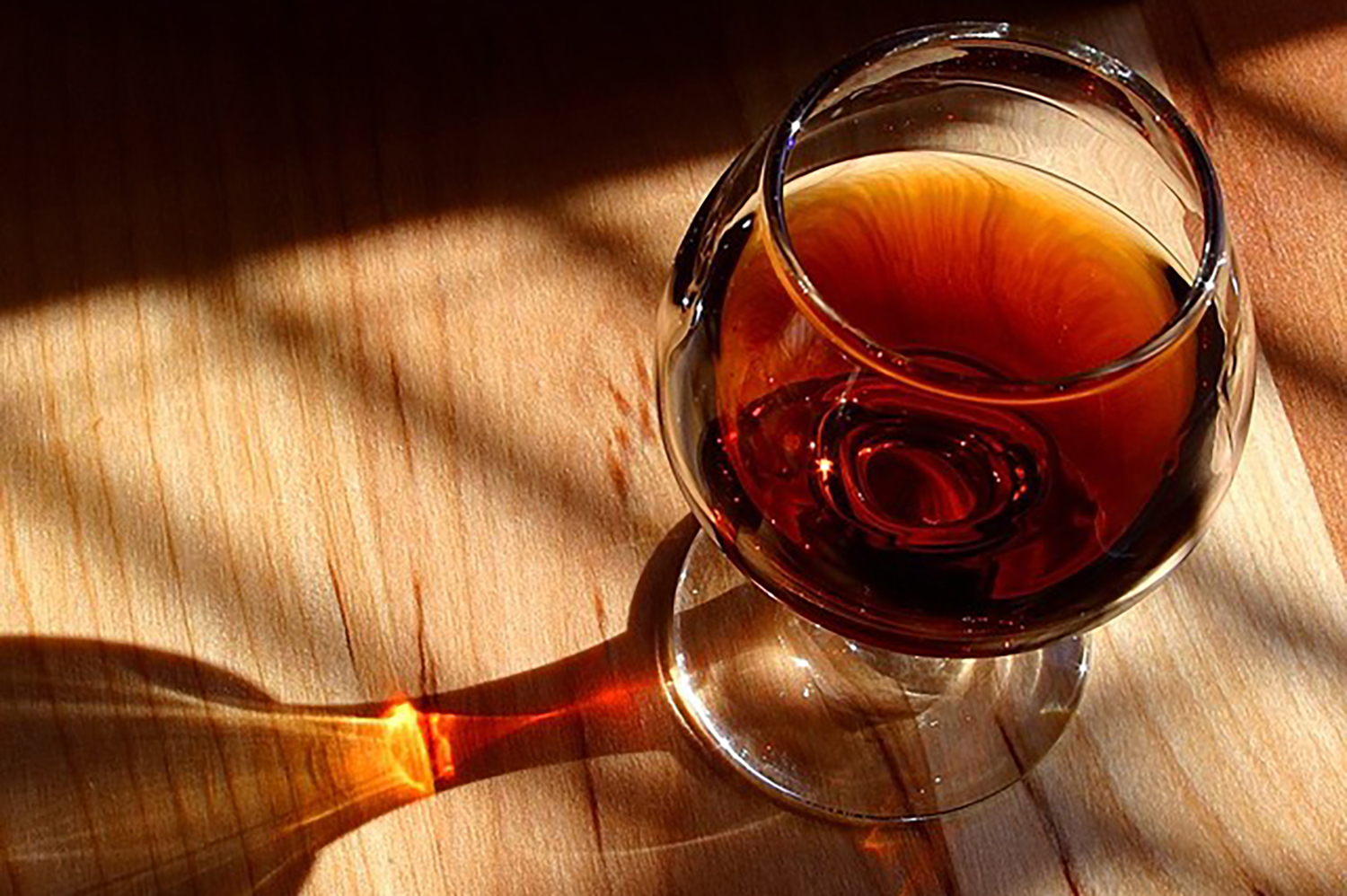 A glass of Cognac served on a wooden table.