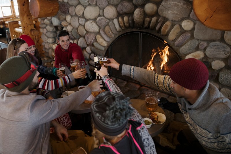 Group of friends gathering in front of a fireplace.