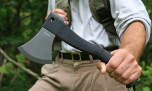 A midsection of a man wielding a hatchet in the outdoors
