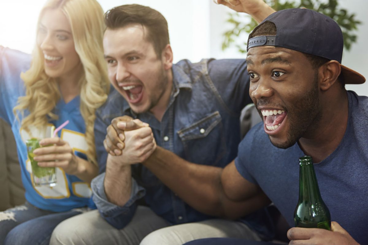 A group of friends cheering while watching a football game.