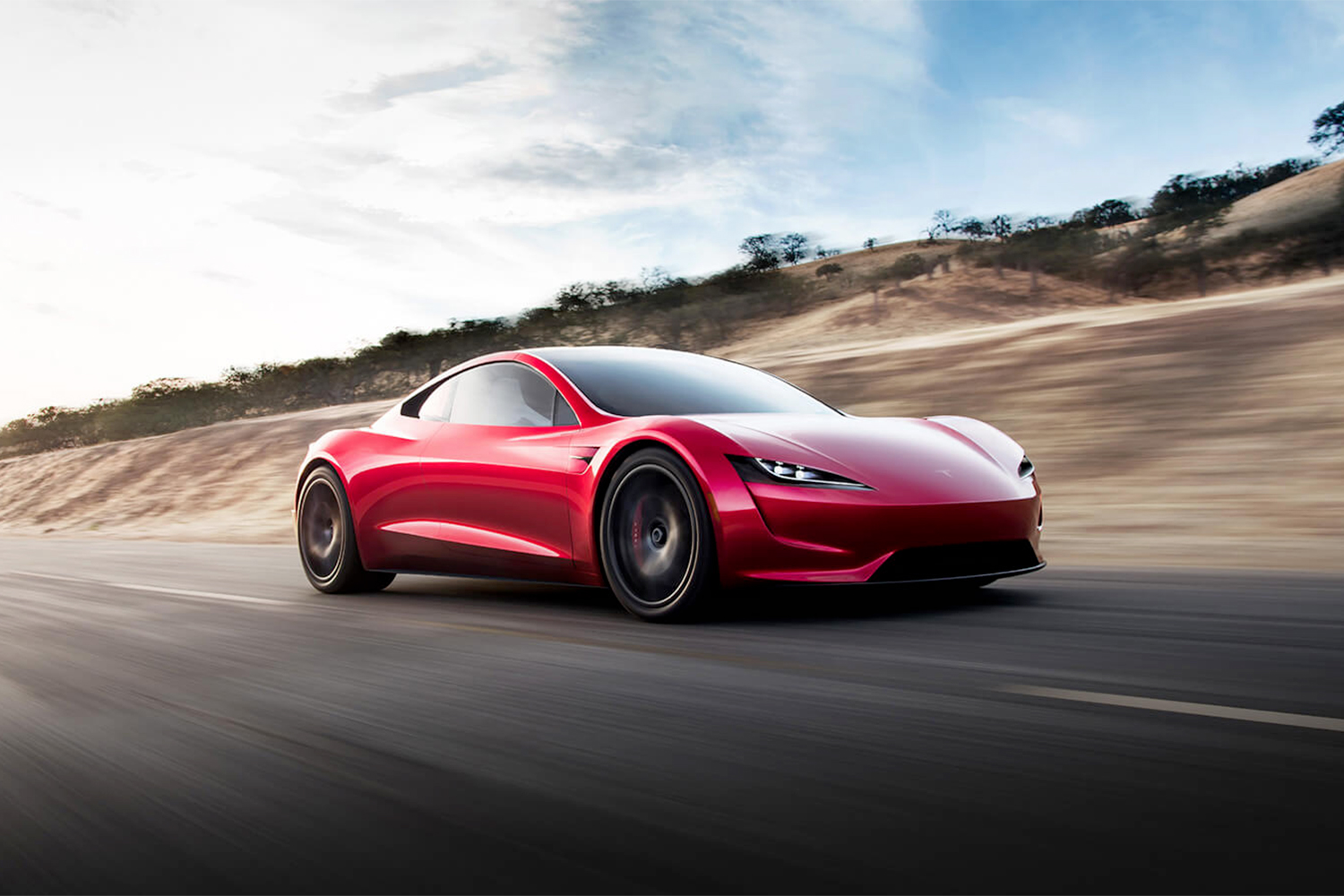 Red Tesla Roadster speeding down a freeway with a blurry background.