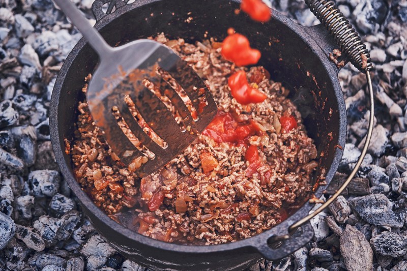 A chili con carne cooks in a Dutch oven