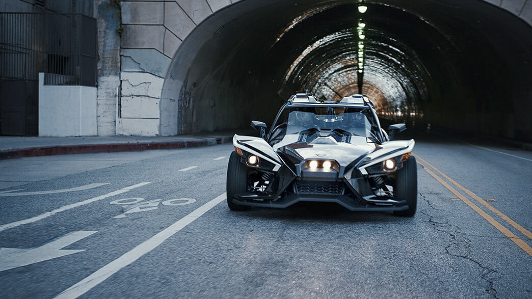 Polaris Slingshot Grand Touring Autocycle racing out of a tunnel toward the camera.