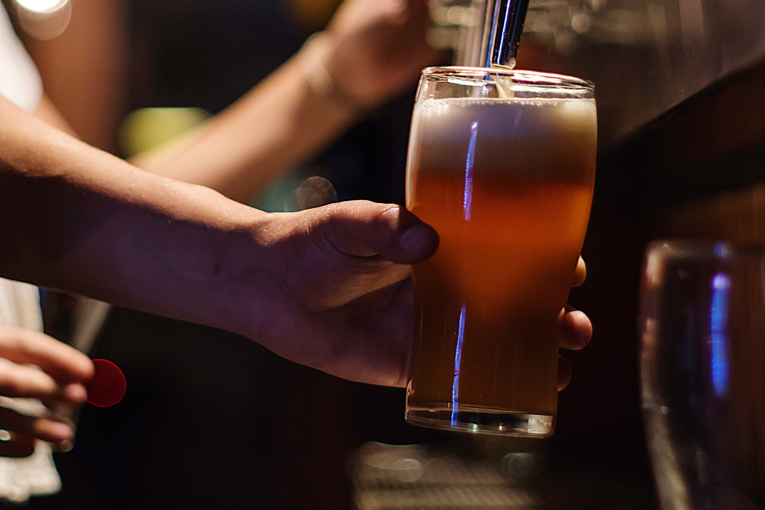 A hand filling a tulip pint glass with beer.