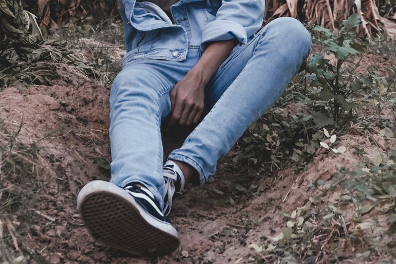 Man dressed in denim sitting on the ground.