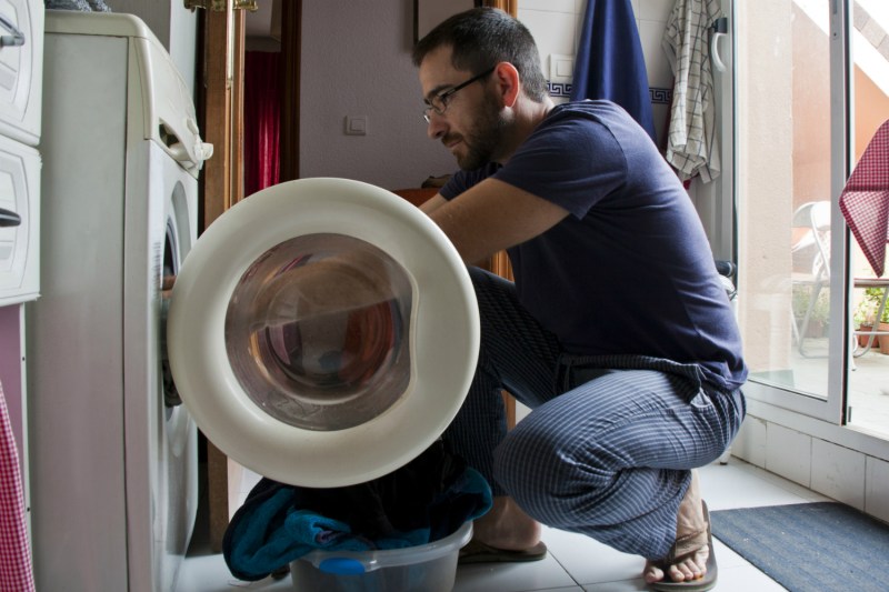 Man kneeling in front of a dryer and removing laundry