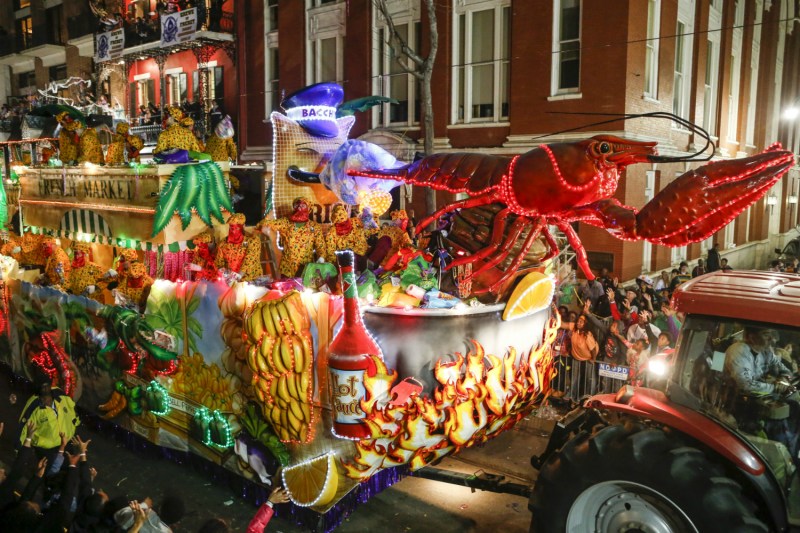 A tractor hauling a float with a huge lobster on the street at night.