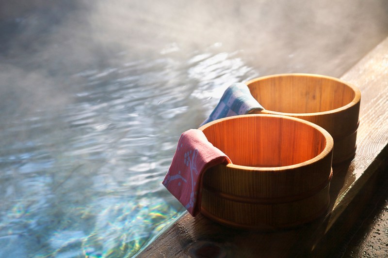 Two towel buckets draped with towels on the side of a Japanese onsen.