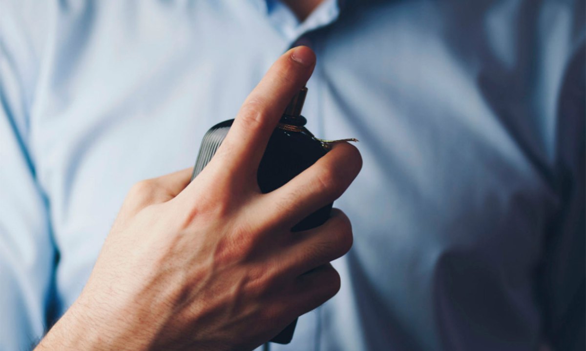A person spraying cologne on themselves.