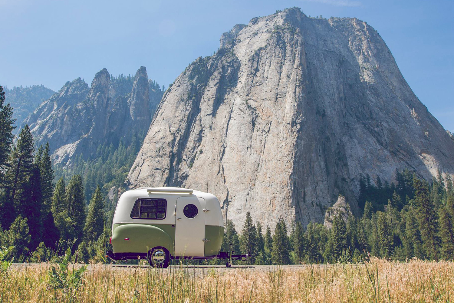 Happier Camper vintage-inspired travel trailer against a mountain background.