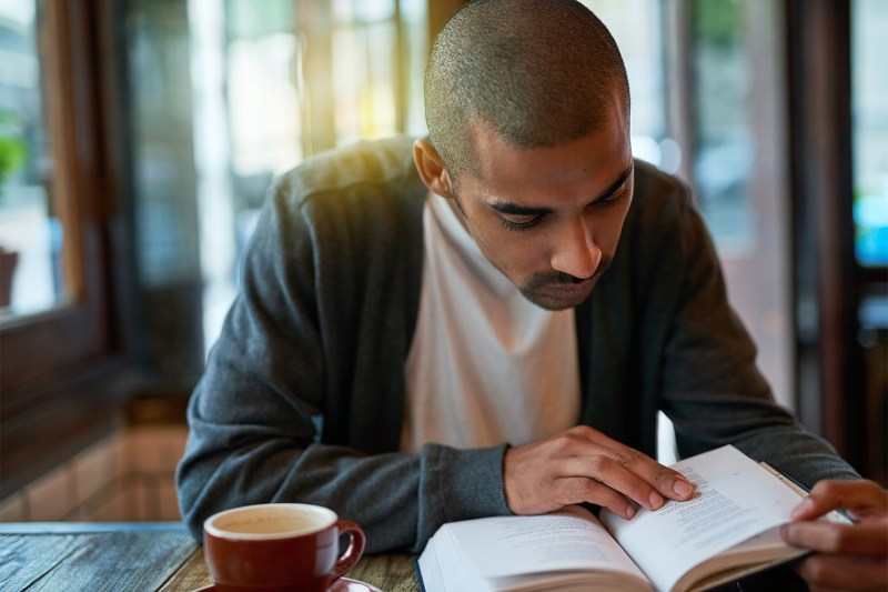 Man reading a book and drinking coffee