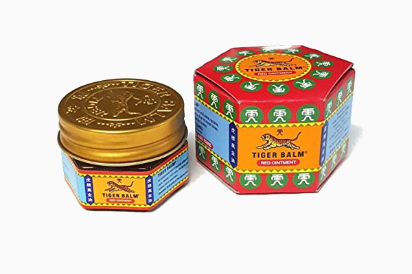 Tiger Balm pain relief cream jar next to a tin can.