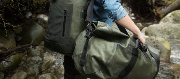 A hiker is seen from behind carrying two large bags.