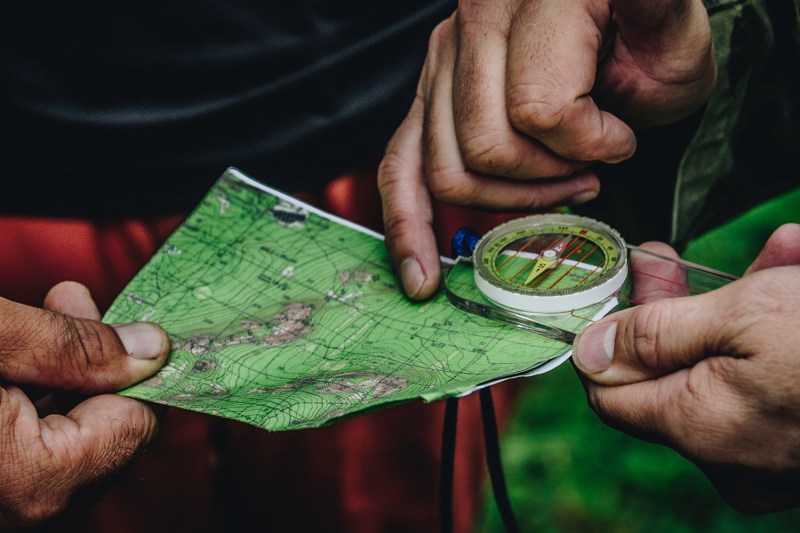 Fingers holding a map and compass in the outdoors