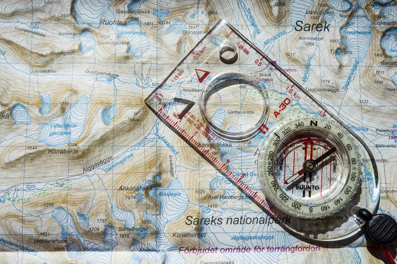 A baseplate compass laid on top of a topographic map