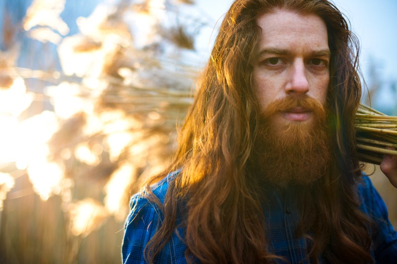Man with long red hair in a field