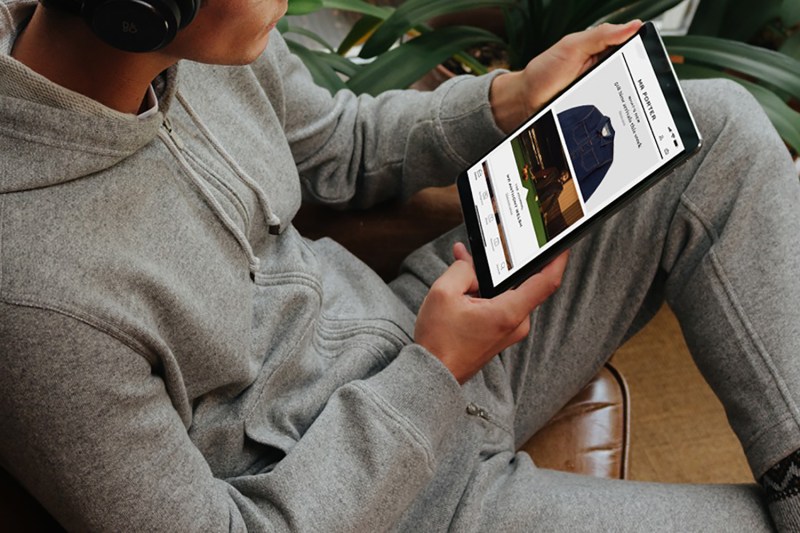 A man using a tablet to shop for clothes on Mr Porter's website.