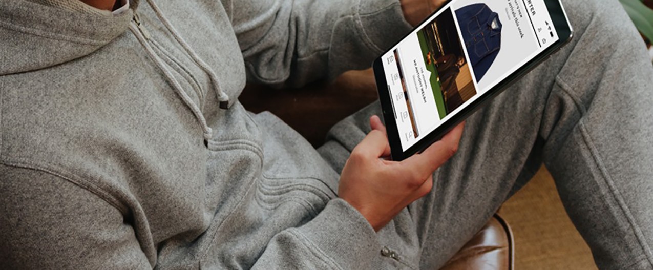 A man using a tablet to shop for clothes on Mr. Porter's website.