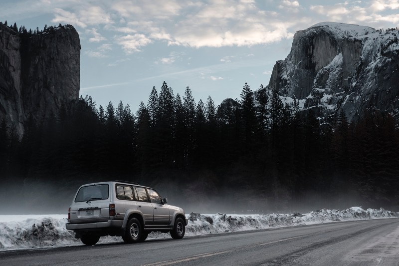 An SUV driving on a mountain pass in winter.