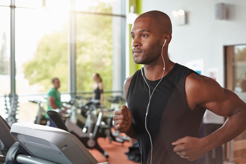 A man with earphones running on a treadmill.