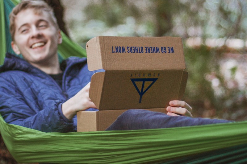 Man in hammock opening a Nomadik subscription box.