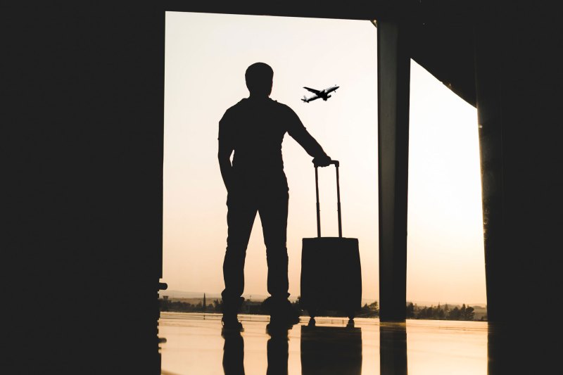 Traveler watching planes from an airport window.