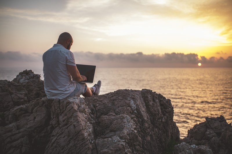 Man working on a laptop on the beach.