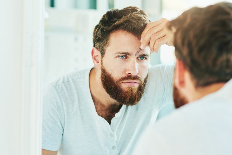 Man tweezing eyebrows