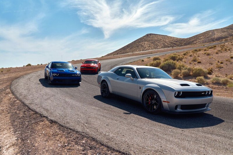 Dodge Challenger SRT Hellcats lined up on a race track in the desert.