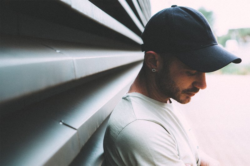 A side profile of a man wearing a cap and white t-shirt.