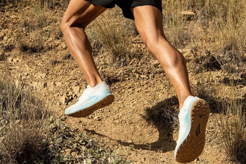 A man dressed in a pair of running shoes running a trail.