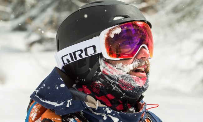 A man wearing a helmet and ski goggles in a snowy area.