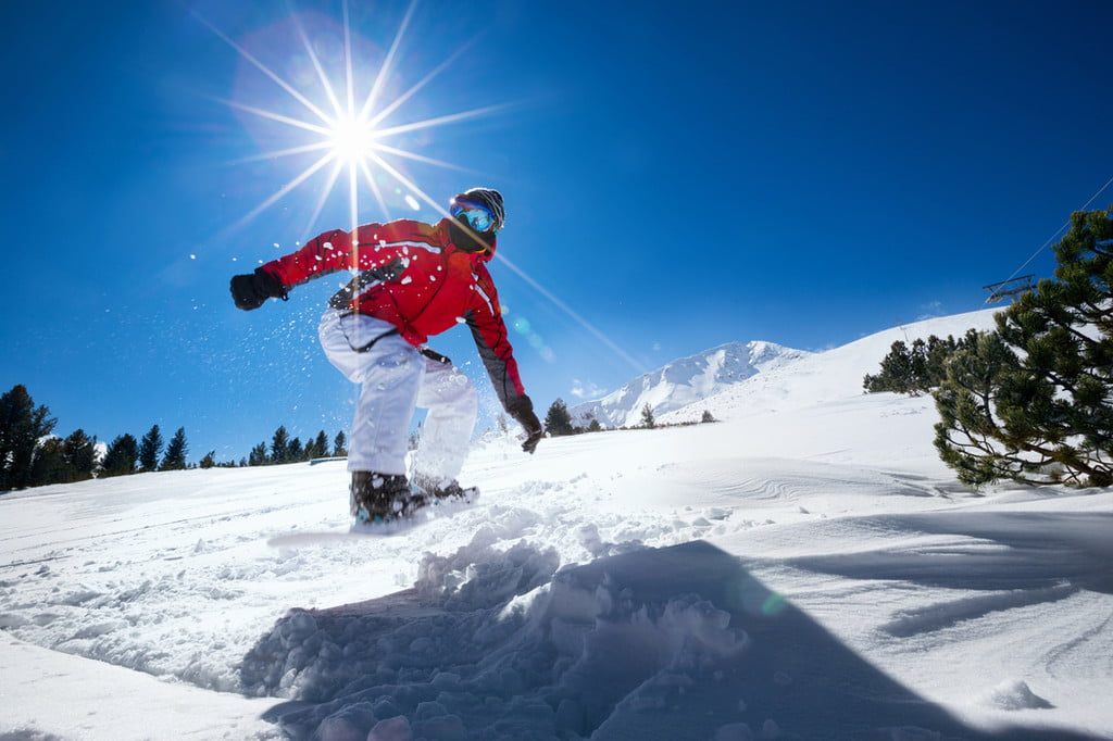 A snowboarder on a slope with the sun in the background