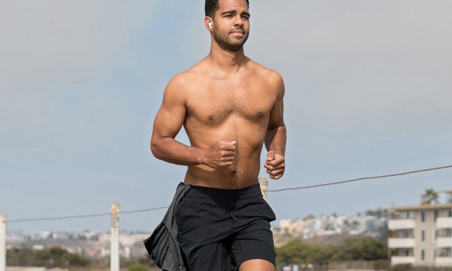 A half-naked man running in workout shorts in the city.