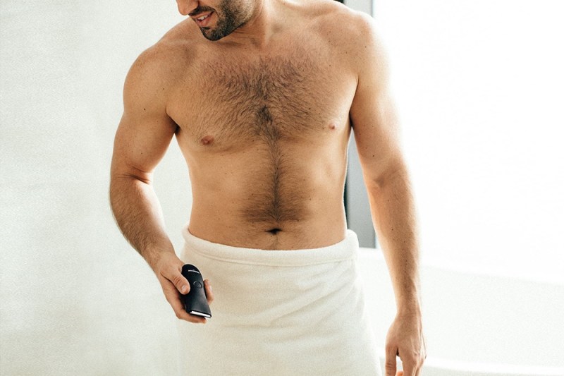 Shirtless man wrapped with towel on the waist down, holding a razor.