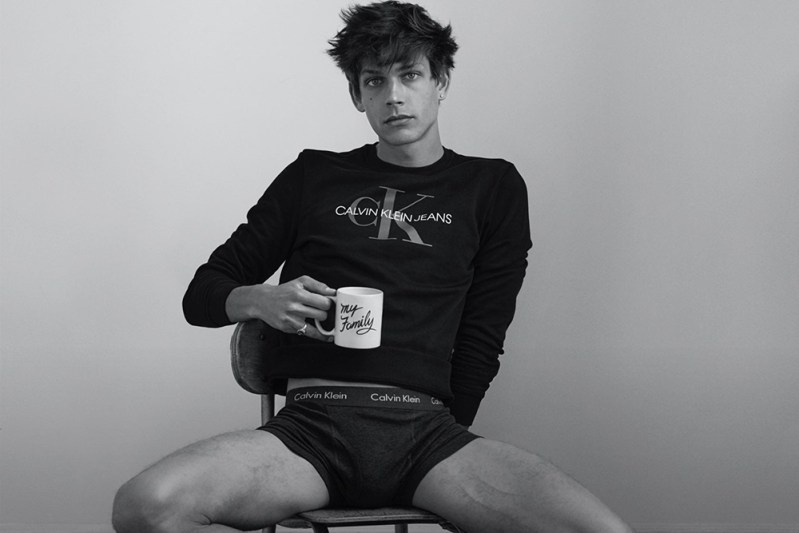 Man holding a mug while wearing a shirt and a pair of underwear from Calvin Klein.