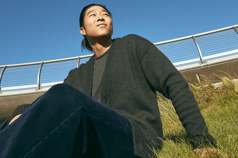 man sitting on a grass wearing a cardigan.