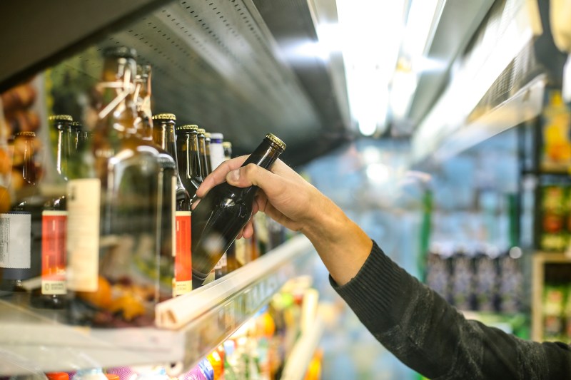 Hand grabbing a bottle from a selection of beers.