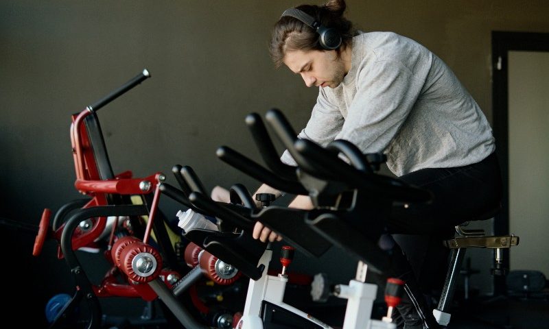 A man riding an exercise bike with headphones on.
