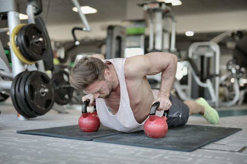 man doing pushups with kettlebells