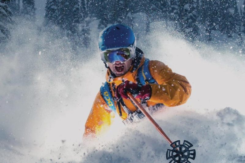 Skier skiing deep powder with a Bern helmet on.