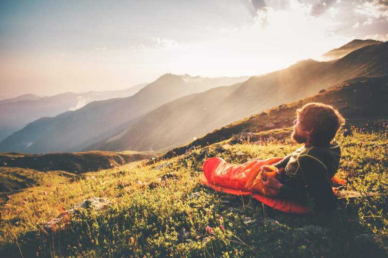 Man reclining on hillside in sleeping bag