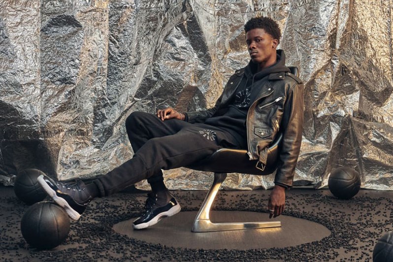 A man in black leather jacket and pants sitting on a chair.