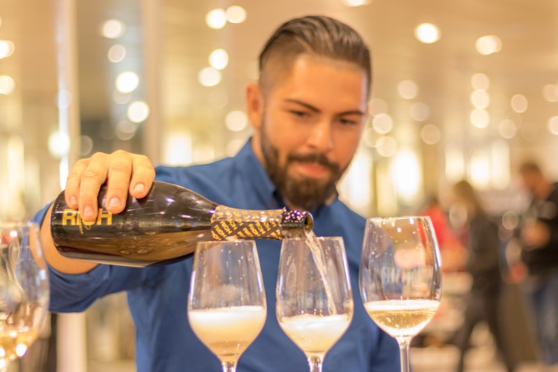 Man pouring three glasses of champagne.