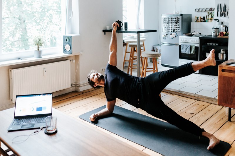 A man doing a side plank on a mat in a home gym.